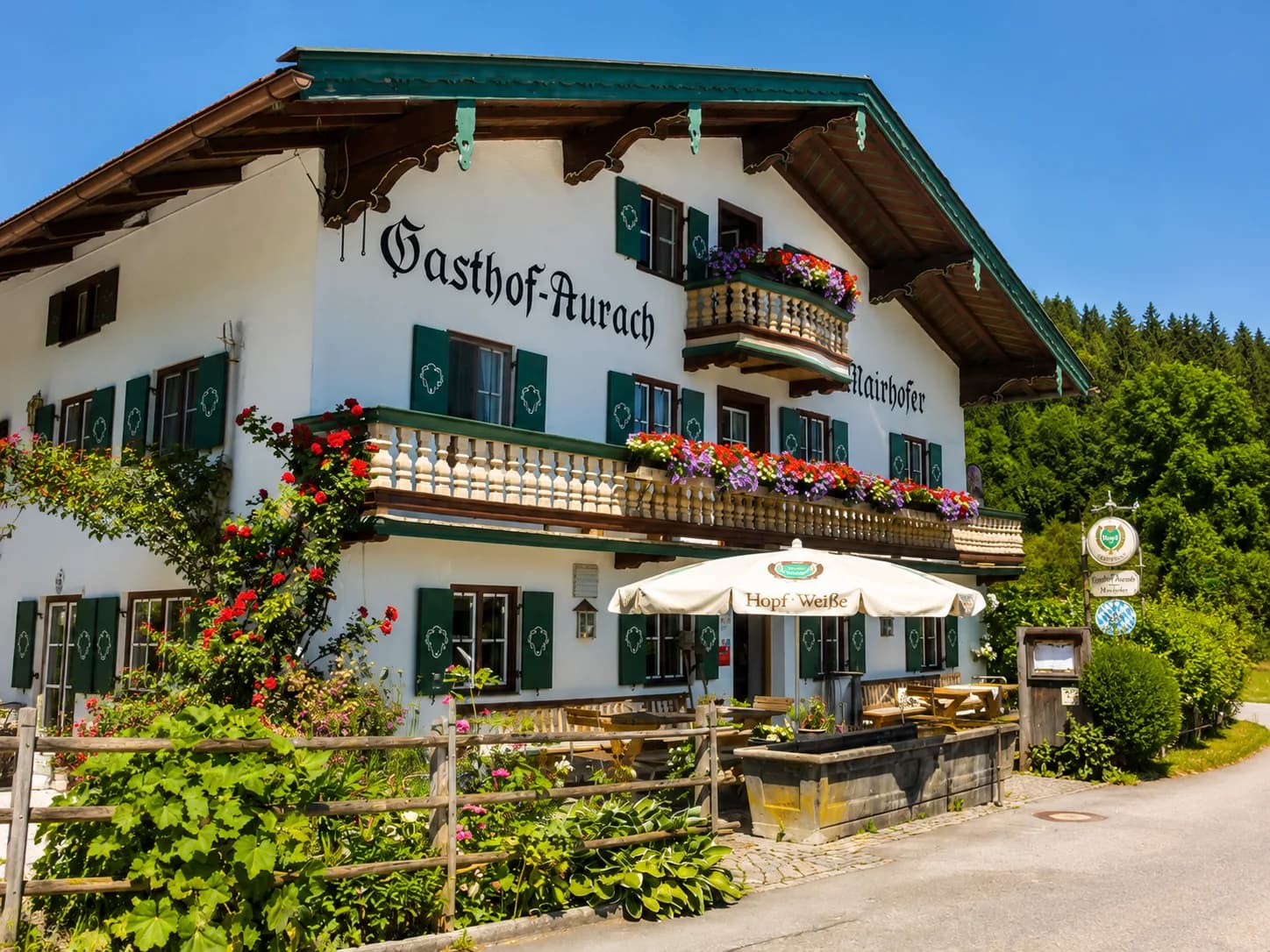 Der Gasthof mit Biergarten und Blumenbeeten an einem Sommertag