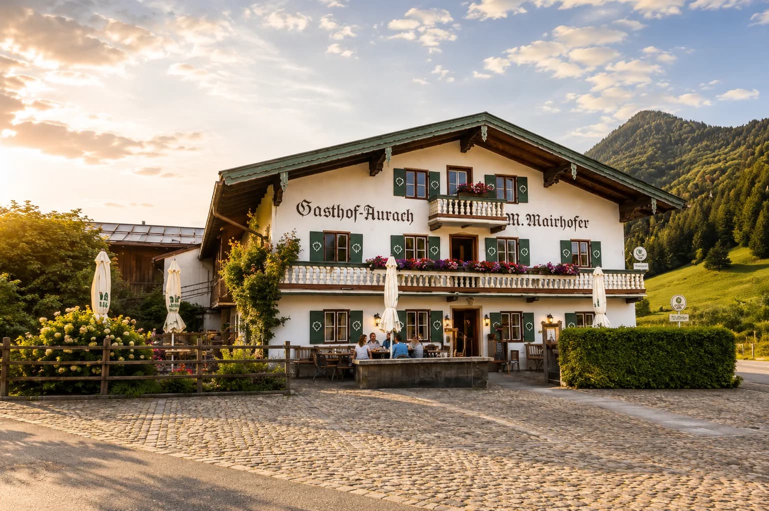 Gäste vor dem Gasthof im goldenen Abendlicht